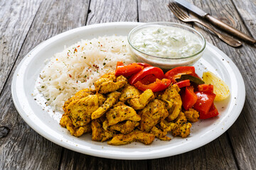 Chicken meat with rice and vegetables on wooden table
