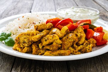 Chicken meat with rice and vegetables on wooden table
