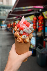 Egg waffle cone with fruits in hand