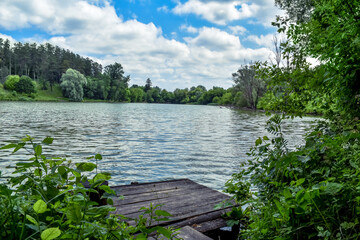 Forest lake with a wooden pier in the village of Uhroidy (Sumy region, Ukraine). Beautiful natural...