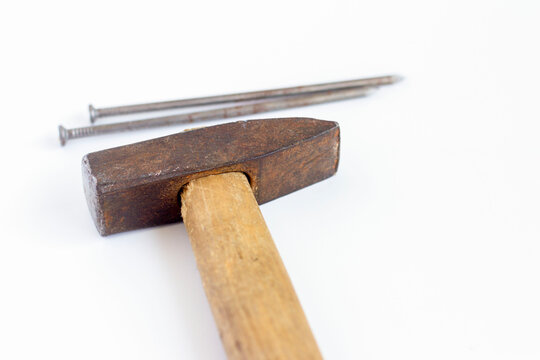 An old hammer and large nails on a white background
