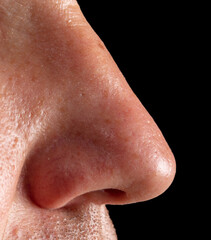 Fototapeta premium Close up of a man's nose isolated on a black background.