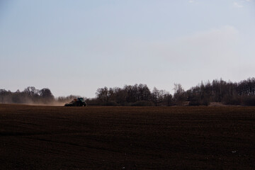 Fototapeta na wymiar a large tractor with a seeder goes through the field.