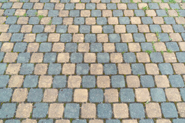 Sidewalk tiles. Closeup of paving slabs background. Street paving slabs. Cement block of the road. Cement brick squared stone floor background. Green grass between the slabs