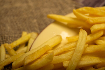 French fries in a round plate on a homespun cloth with a rough texture. Close up.