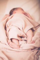 Portrait of a cute adorable white Caucasian baby newborn in diaper, sleeping dreaming, lying on bed, covered with blanket, view from top above. Cute little baby sleeping on bed at home.