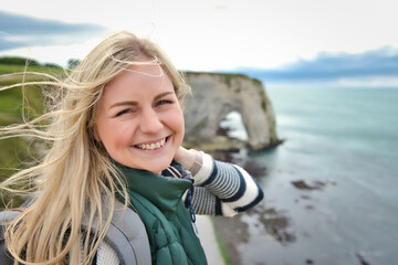 Blond woman exploring the coast of France brittany at Étretat