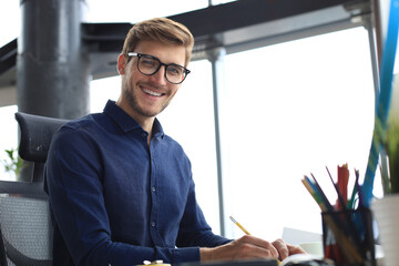 Good looking young business man drawing something while working in the office.