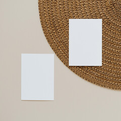 Blank paper cards with mockup copy space and wicker napkin on beige background. Minimal business...