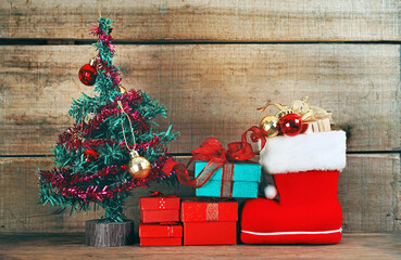 Group of gift boxes with red boot decorate near christmas tree with wood background