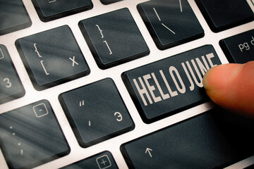 Handwriting text writing Hello June. Conceptual photo a new month to plan your activities for fun and adventures Pc keyboard key with pointing finger above background copy space