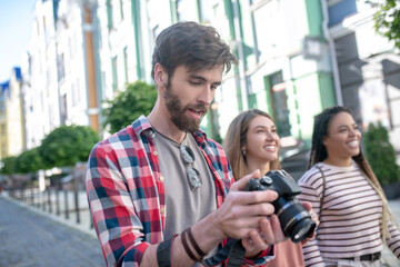 Focused guy watching pictures on camera while walking around city