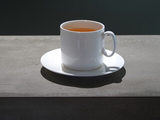 White ceramic cup with green tea on a dark table.