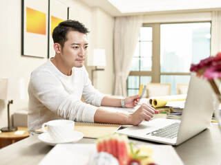 Fototapeta na wymiar young asian man designer working from home using laptop computer contacting client