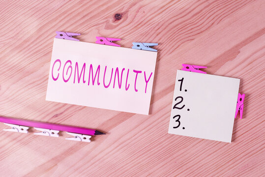 Word writing text Community. Business photo showcasing group of showing with a common characteristics living together Colored clothespin papers empty reminder wooden floor background office