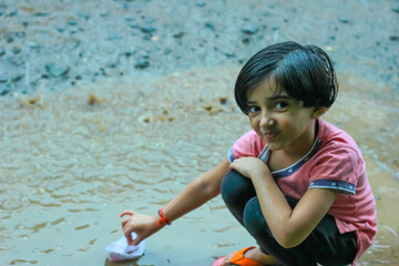 indian girl playing with paper boat
