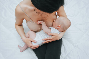 A small, recently born baby lies in her mother's arms and eats breast milk. Breastfeeding at 3, 4...