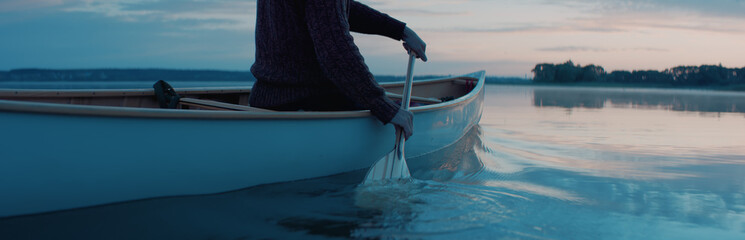 CU view of a paddle, man canoeing alone boat on a large lake at dawn