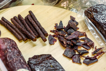 Slices of jerky lie on a wooden board.
