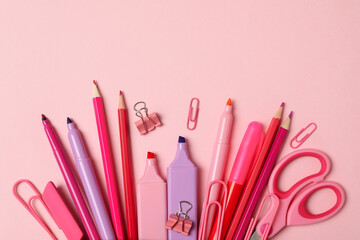 Pink pencil case with different supplies on pink background