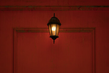 Fototapeta na wymiar Vintage lantern with ecological safe lamp on red old wall.