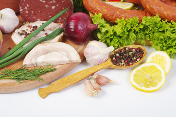 Meat products, sausages, vegetables, herbs, spices on the kitchen board.