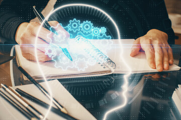 Double exposure of writing hand on background with brain hologram. Concept of learning.