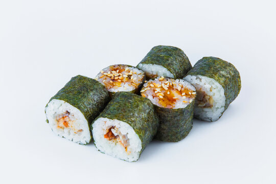 Side view of Japanese Unagi Maki Roll with eel and rice wrapped in nori seaweed, served with sauce and sesame seeds. Close-up of asian traditional dish isolated on background. Isolation menu image
