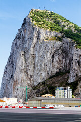 Gibraltar airport - crossing a road with a runway. In the background Gibraltar Rock