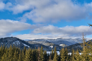 Winter landscape from the mountain with lake, fir forest, snow and blue sky with clouds