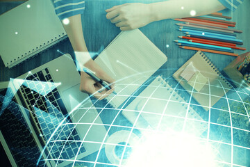 Double exposure of hands making notes with world map hologram and data theme icons. Concept of international network data.