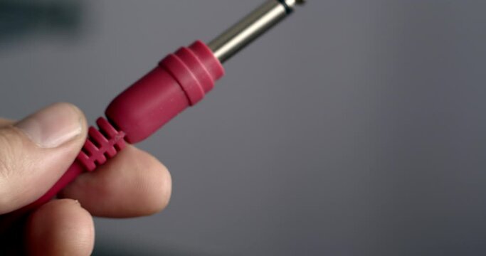 close up of hand holding a red jack plug