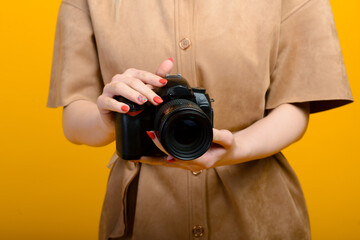 Image of hands with digital photo camera on empty yellow background