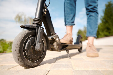 Tyre of wheel of electric scooter of contemporary woman standing on the road