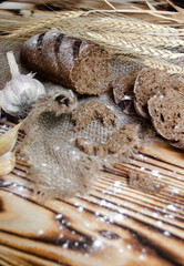 black bread on a wooden background with wheat ears