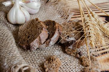 black bread on a wooden background with wheat ears