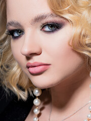 Gorgeous blonde, portrait on a black background. Beautiful young girl, makeup for the celebration.