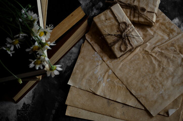 a stack of old books on the table with a bouquet of daisies