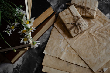 a stack of old books on the table with a bouquet of daisies