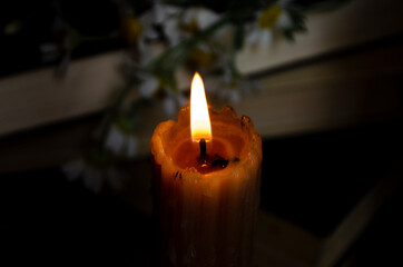 vintage candle on the table with a stack of books and daisies