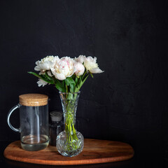 Beautiful and lush white peonies in a vase on a black background,