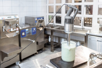 Mixed milkshake and professional blender on the table at the kitchen, making a base for ice cream or yogurt
