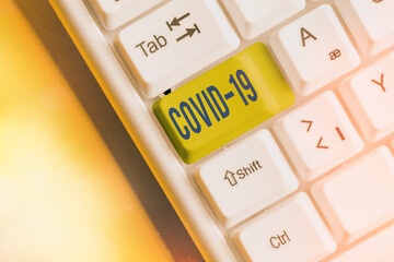 Writing note showing Covid19. Business concept for mild to severe respiratory illness that is caused by a coronavirus White pc keyboard with empty note paper above white key copy space