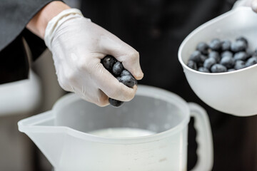 Chef mixing blueberries with milk, making base for ice cream or yogurt, close-up