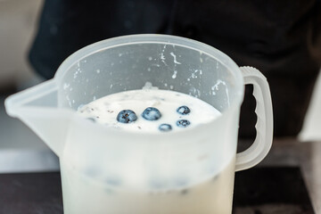 Blueberries with milk in the jar, preparing base for ice cream or yogurt, close-up