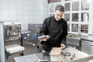 Confectioner pouring chocolate on the ice cream, making ice cream on the kitchen of a small...