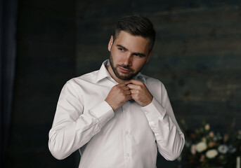 Portrait of serious and confidence man. Man fastens his white shirt.