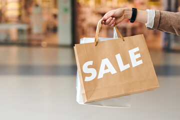 Hand of young contemporary shopaholic holding bunch of sale paperbags