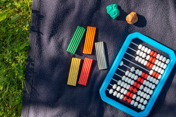 School supply, plasticine and abacus on plaid, picnic concept