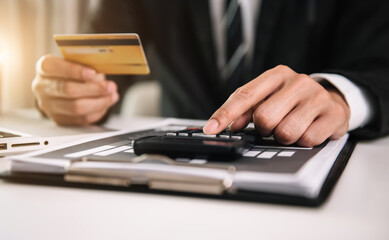 Businessman using calculator with credit card for shopping internet online in office.